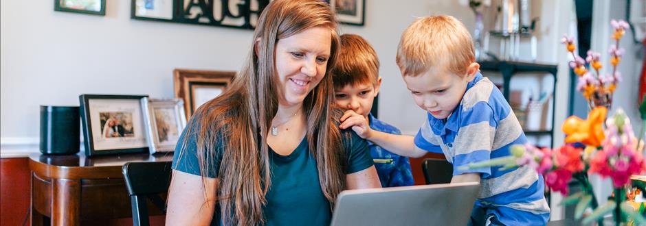 Military spouse on computer with her young children.