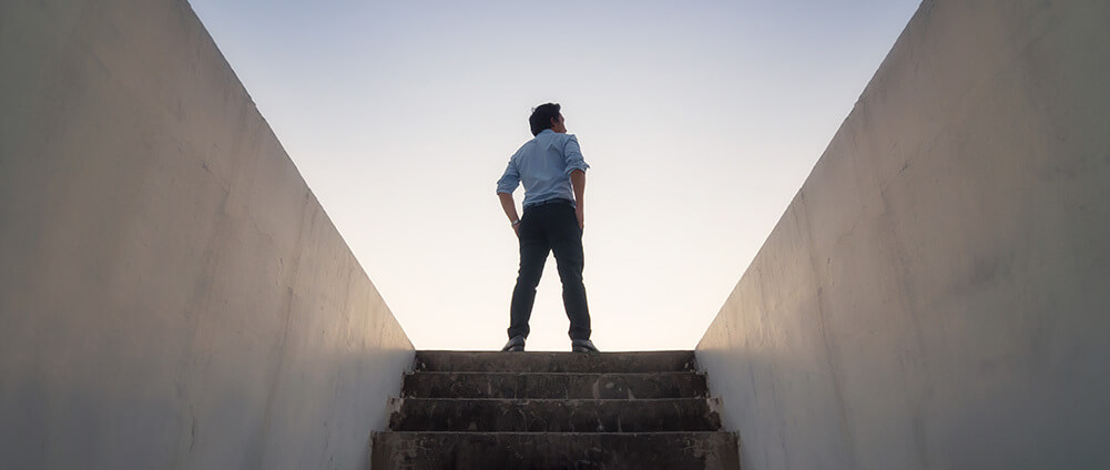 man on top of stairs with hands on hips
