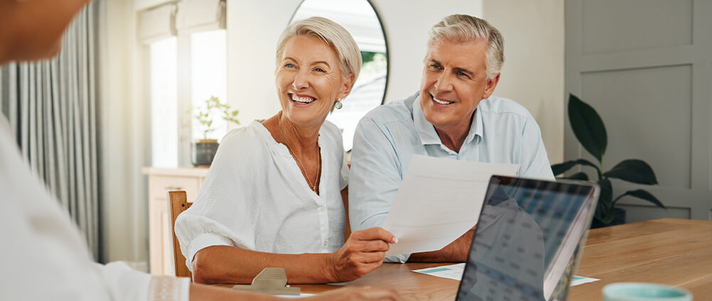 man and woman smiling and holding a piece of paper