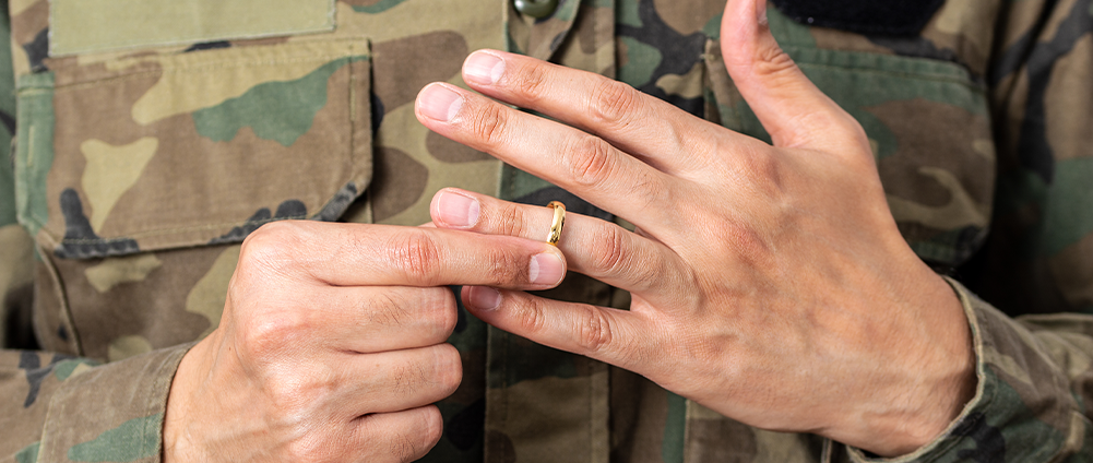 US servicemember wearing camo takes off wedding ring as part of a military divorce. AWM&T provides financial considerations.
