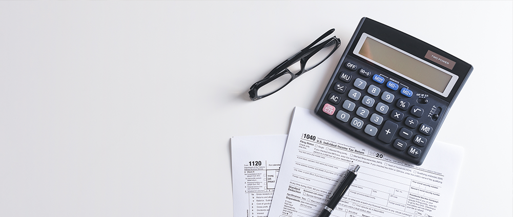 Calculator, glasses, pen and tax forms from the IRS.