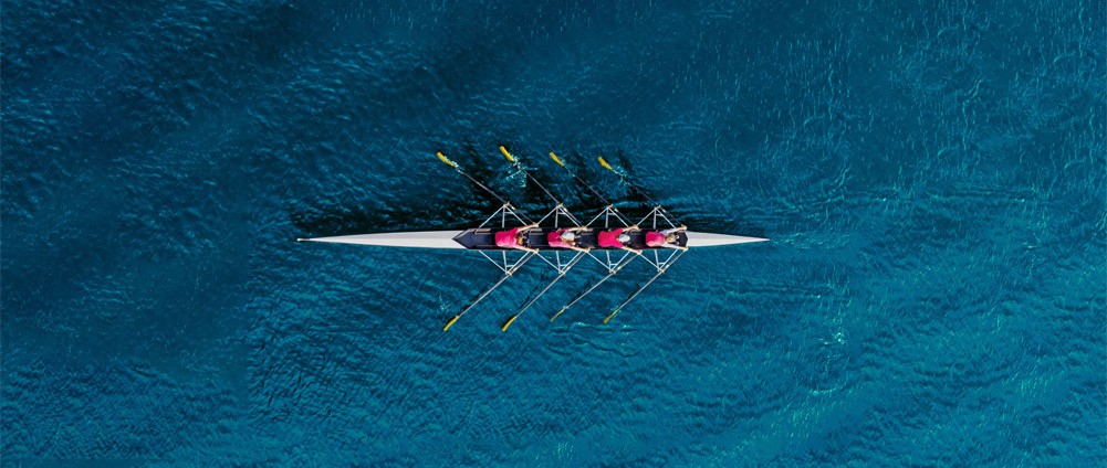 Team rowing a boat.